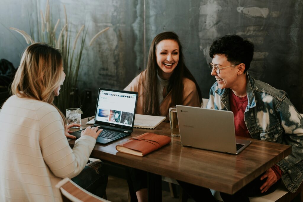 group of colleagues laughing at table with laptops